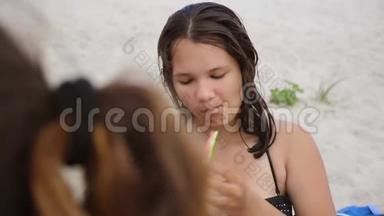 孩子们在海滩上吃西瓜。 女孩少年长着粉刺吃西瓜。 概念女孩和西瓜